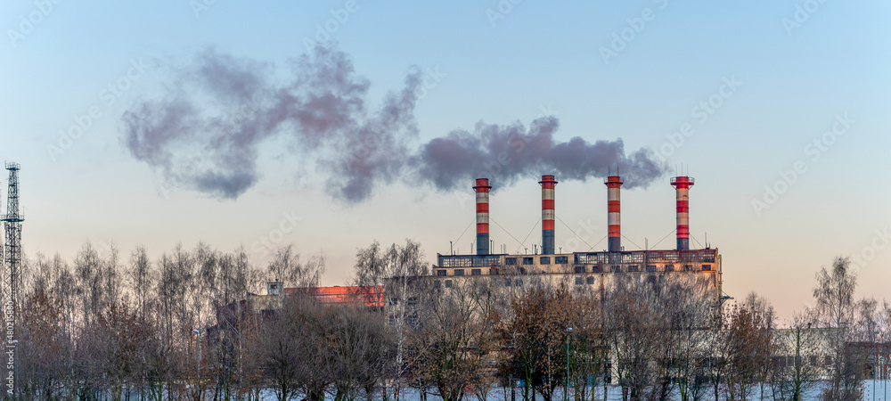 Obraz premium Industrial air pollution. Winter landscape with factory and trees. The concept of environmental pollution.