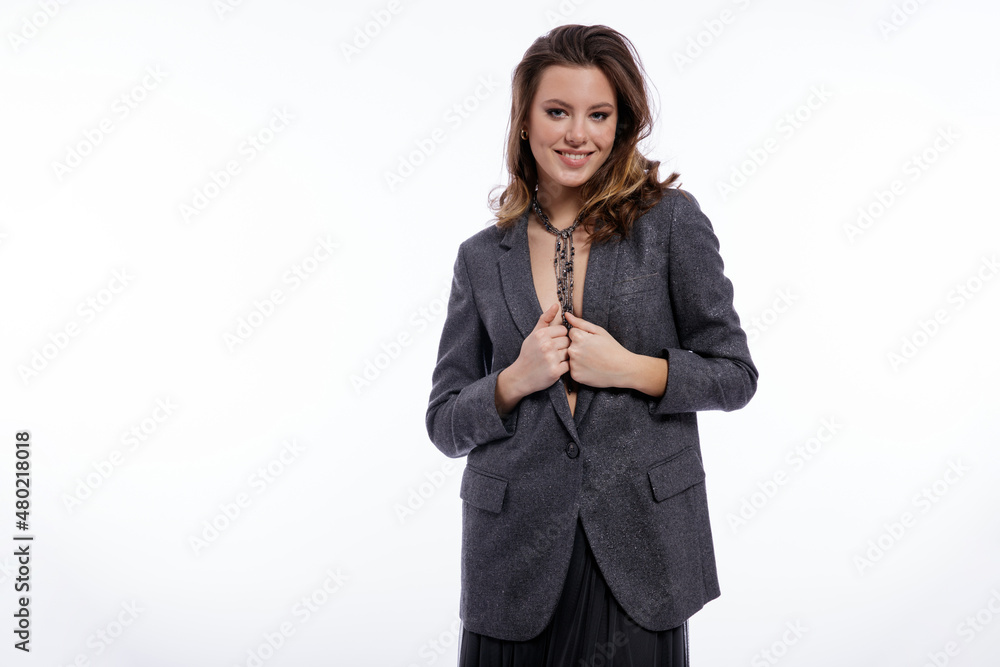 High fashion photo of beautiful elegant young woman in a pretty suit, gray sequined jacket, long skirt, snake skin boots, necklace posing on white background. Studio shot. Luxury hair, shiny curls High fashion photo of beautiful elegant young woman in a pretty suit, gray sequined jacket, long skirt, snake skin boots, necklace posing on white background. Studio shot. Luxury hair, shiny curls