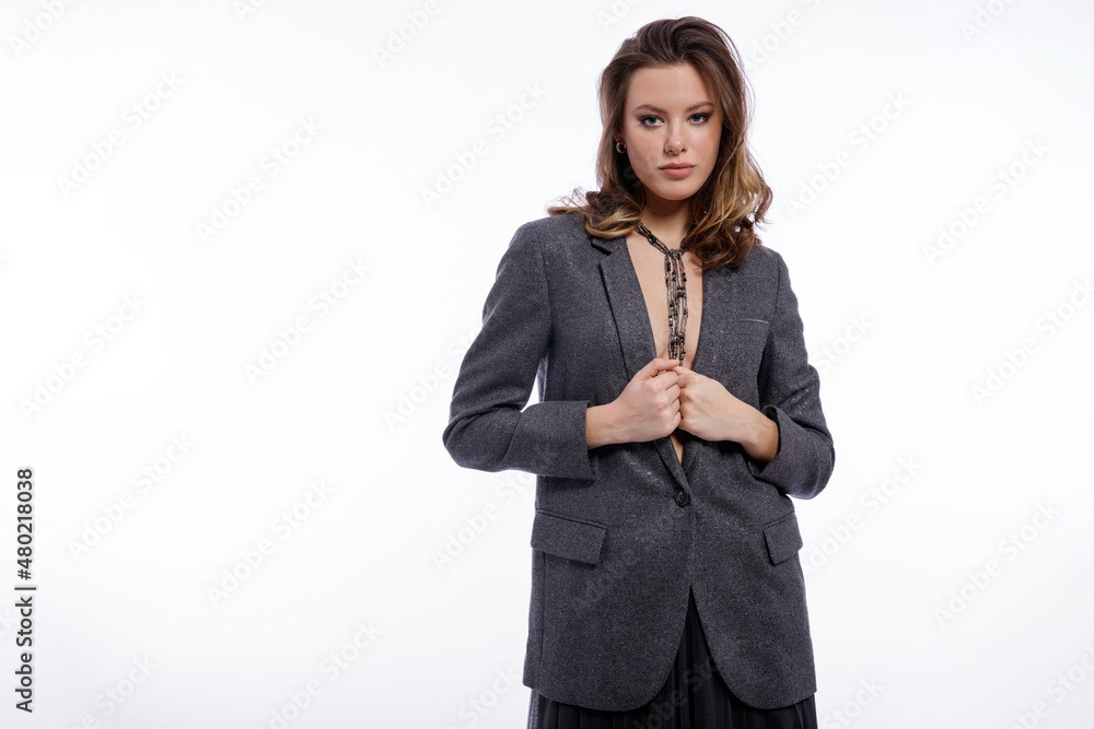 High fashion photo of beautiful elegant young woman in a pretty suit, gray sequined jacket, long skirt, snake skin boots, necklace posing on white background. Studio shot. Luxury hair, shiny curls High fashion photo of beautiful elegant young woman in a pretty suit, gray sequined jacket, long skirt, snake skin boots, necklace posing on white background. Studio shot. Luxury hair, shiny curls