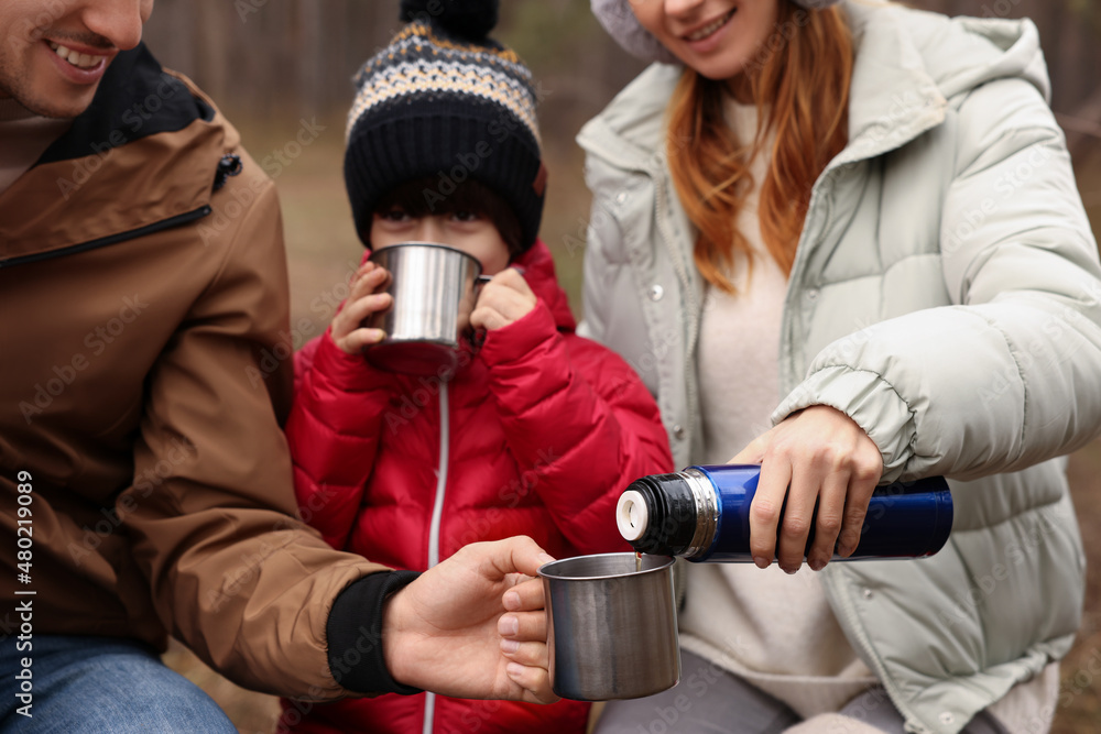 Naklejka premium Happy family drinking hot tea together in forest, closeup