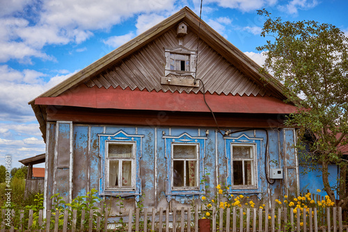 A traditional old wooden house with a front garden. Summer view.