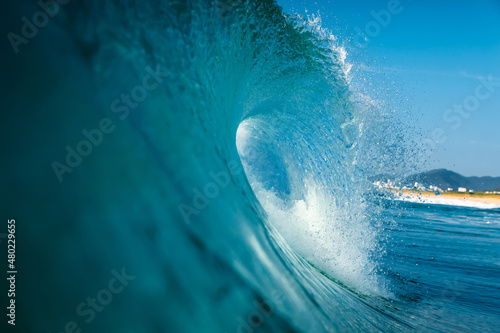 Surfing wave in Atlantic ocean. Blue glassy barrels and clear sky