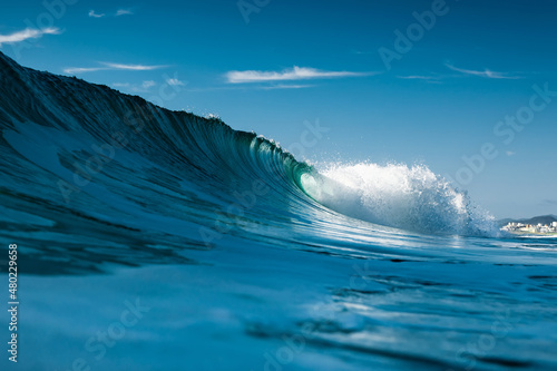 Ideal surfing wave in Atlantic ocean. Blue glassy barrels and sky