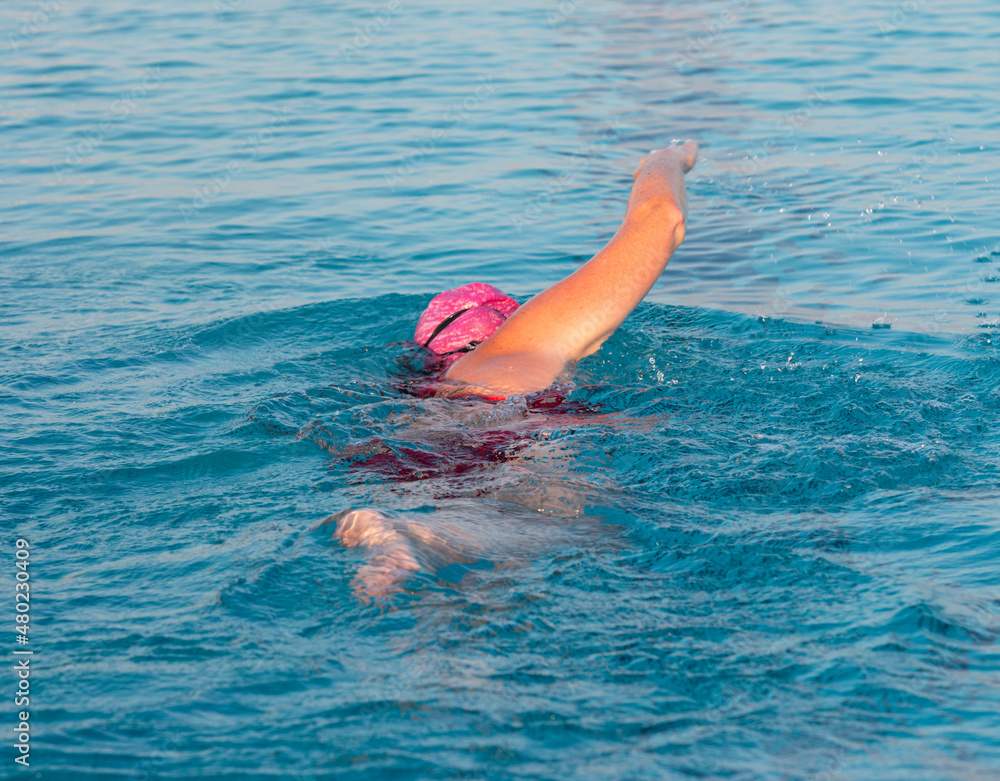 Women swimming in a pool wearing a pink bathing cap
