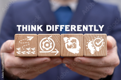 Think differently business concept. Man holding wooden cubes with icons and think differently text. Being different. Be unique and creative.