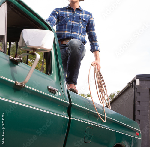 Cowboy hold rope standing on back of truck photo