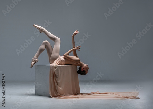 Obraz na plátně Ballerina dancing on ballet pointe shoes in body color leotard and long cloth in