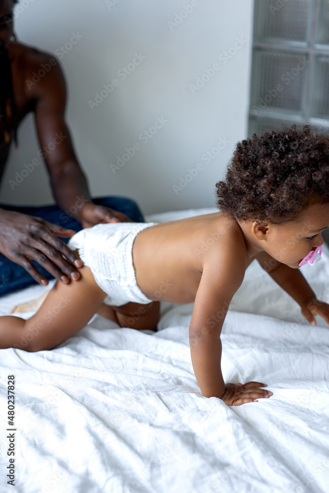Obraz premium nice adult man with dark skin having rest on bed at home, in the morning. handsome shirtless guy enjoy parenthood. in domestic atmosphere. free time, weekends, leisure concept