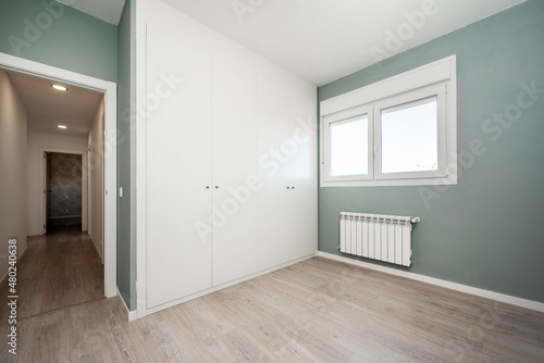 Room with one wall painted in light green and another covered with a large white built-in wardrobe © Toyakisfoto.photos
