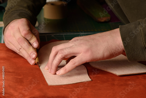 Obraz na płótnie Shoemaker hands cutting terracotta suede leather in workshop. Closeup. w salonie