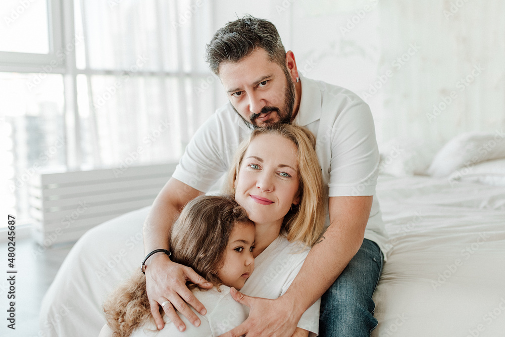 Happy young family. Man, woman and daughter. Light background, studio shot. Interracial marriage, different nationalities Happy young family. Man, woman and daughter. Light background, studio shot. Interracial marriage, different nationalities