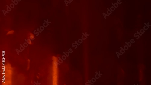 Cloud of smoke hovers and moves against background of dark empty studio in the rays of yellow red lighting stage lights. Colorful lighting effects on smoky dark nightclub stage. Close up. Slow motion. photo