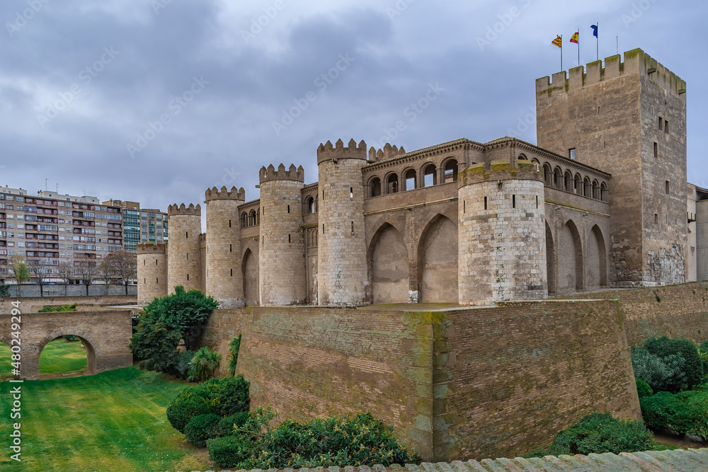 Exterior view of Aljaferia Palace in Zaragoza, Spain. Traditional fortified medieval castle surrounded by a moat with a green lawn
