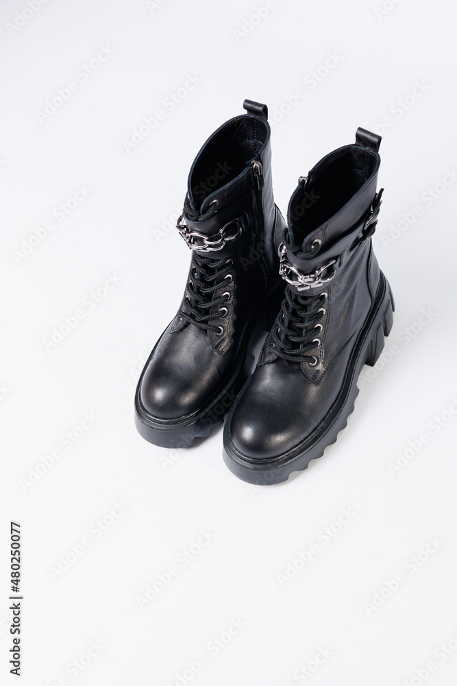 Women's shoes on a white background. Close-up of women's black leather boots with buckles on a white background. Shoes for the city. Concept for 2022 fashion, design and footwear. Women's shoes on a white background. Close-up of women's black leather boots with buckles on a white background. Shoes for the city. Concept for 2022 fashion, design and footwear.