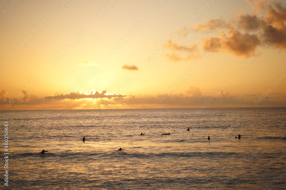 Surfers waiting for a wave while the sun sets