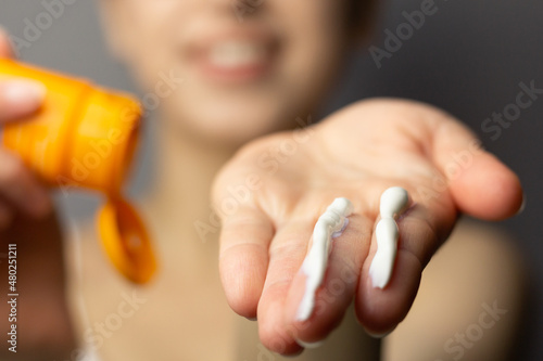 Young woman applying the correct amount of sunscreen for face and neck.