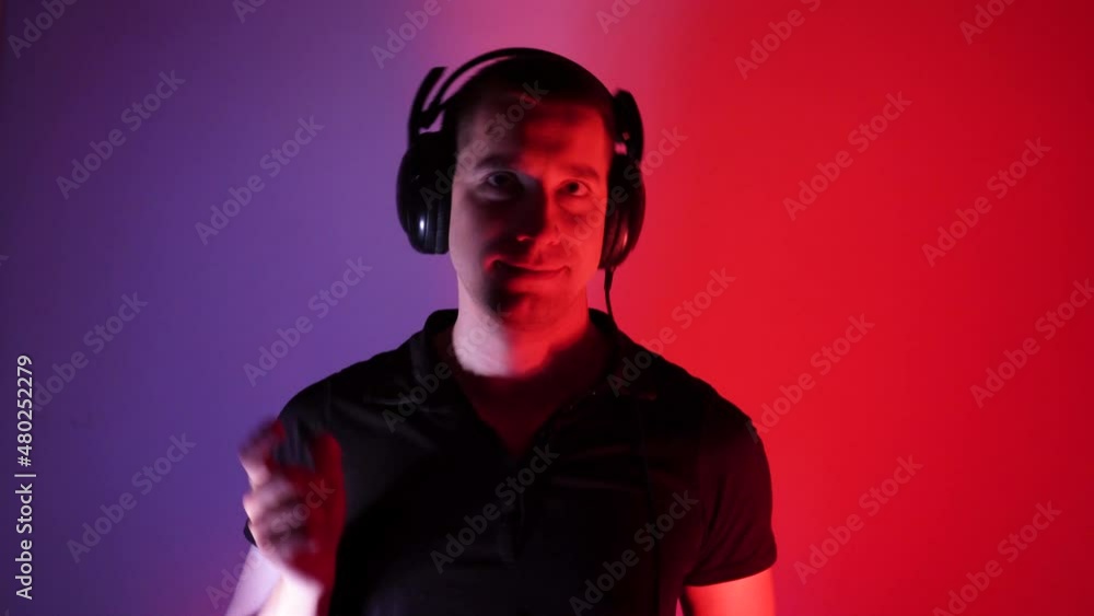 Excited young man in headphones is dancing in the club. Modern rave. Dance with fluid hand movements to the rhythm. Music lover Excited young man in headphones is dancing in the club. Modern rave. Dance with fluid hand movements to the rhythm. Music lover