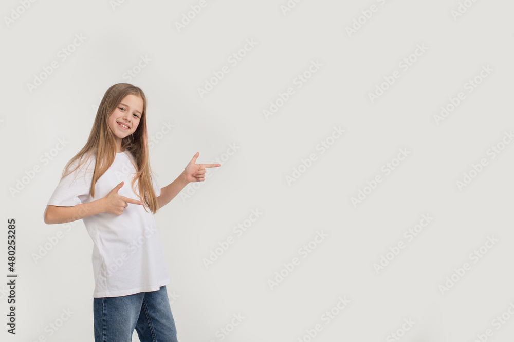 a beautiful teenage girl points her fingers to the side on a white isolated background. place for text a beautiful teenage girl points her fingers to the side on a white isolated background. place for text