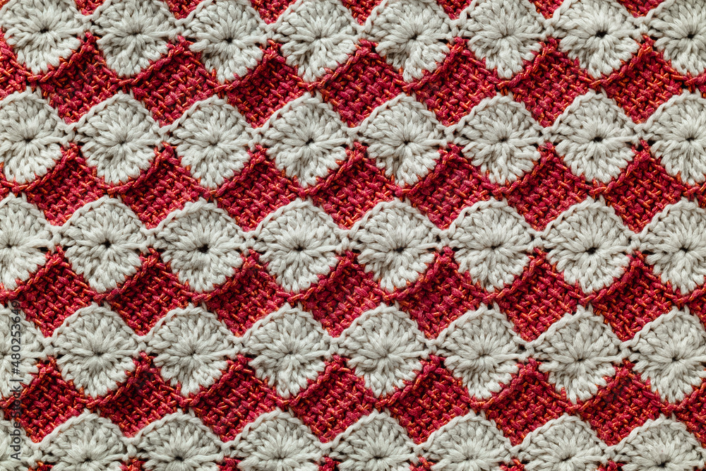 White and red crocheted floral pattern. Knitted texture.