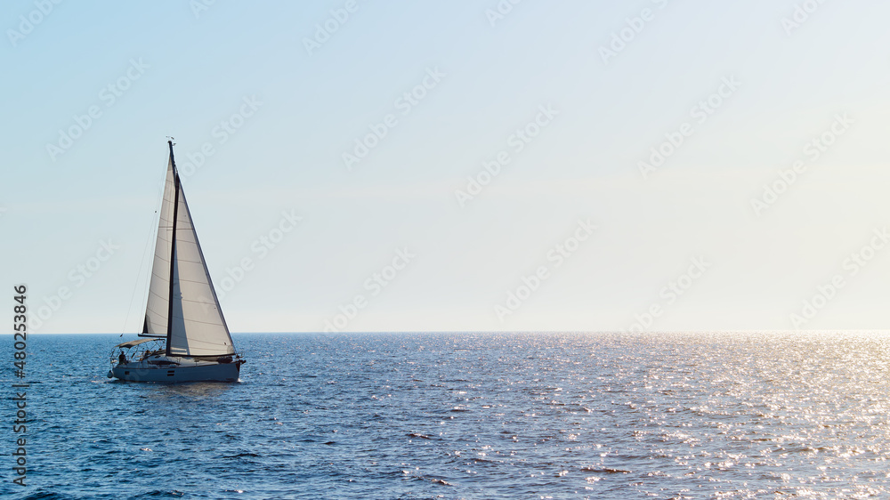 Luxury yacht sailing under white sails on the blue azure sea on a sunny summer day. The concept of travel, yachting, regattas. Copy space
