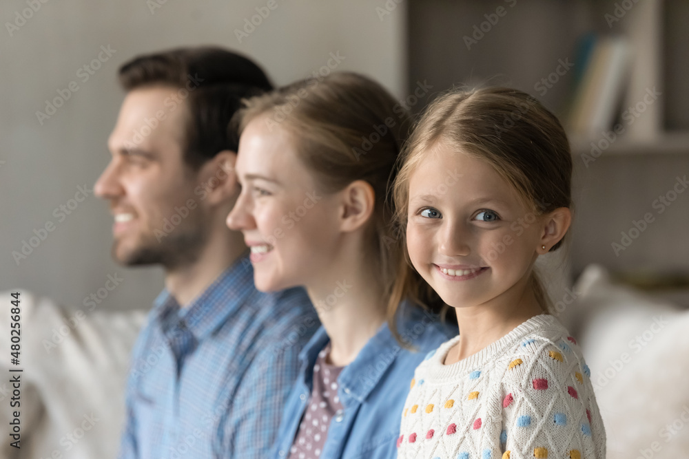 Head shot smiling adorable preteen small child girl looking at camera while happy young couple parents looking in distance, friendly two generations family heredity, dynasty, union, relations concept. Head shot smiling adorable preteen small child girl looking at camera while happy young couple parents looking in distance, friendly two generations family heredity, dynasty, union, relations concept.