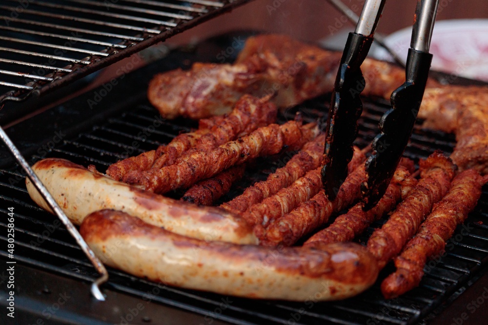 Grilled meat on a gas grill with grill tongs