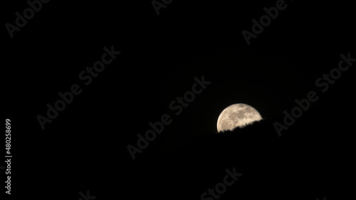 Moon rising over hills in complete darkeness