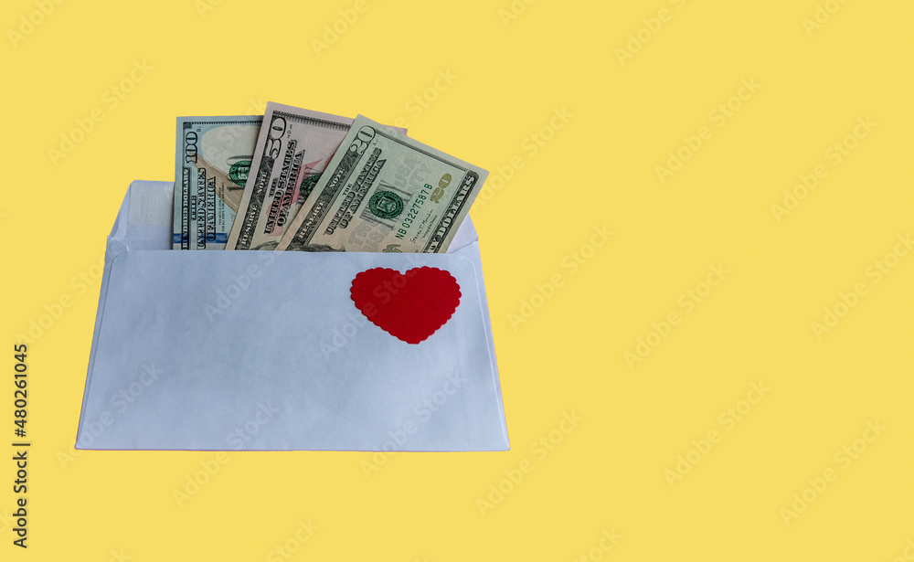 Red heart on a paper envelope with dollars on a yellow background. Banknotes stick out from the envelope. Conceptual gift for Valentine's Day, wedding, birthday. With copy space to add text.