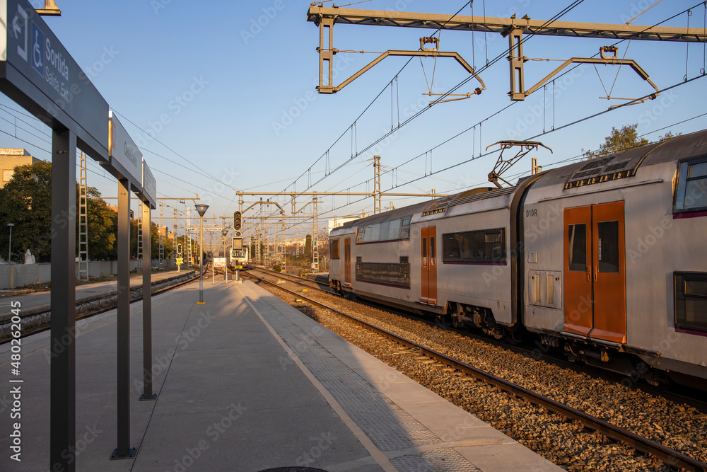 Rail travel. Modern intercity train on a railway platform. Passenger train on the railway in the evening. Railway station Castelldefels. Platform, rails and wires going into perspective.