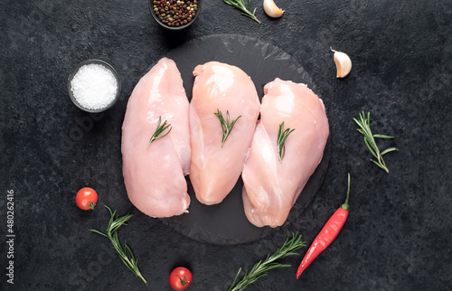 Three raw chicken breasts on stone background