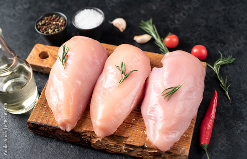 Three raw chicken breasts on stone background