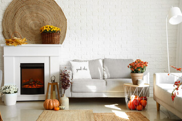 Cozy interior of living room with fireplace, sofa and autumn decor