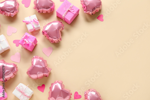 Heart-shaped air balloons and gifts for Valentine's day on beige background