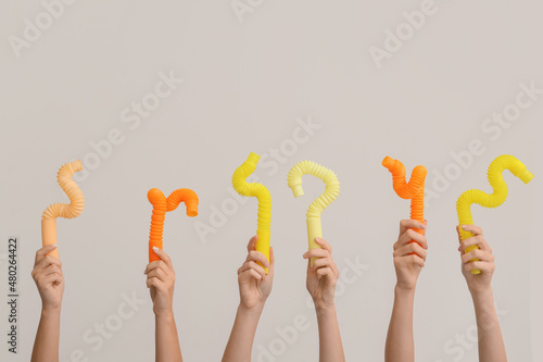 Hands with popular pop tubes on light background