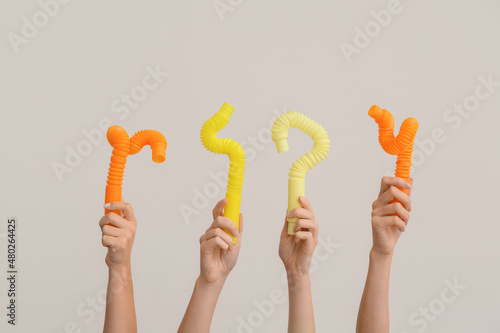 Hands with popular pop tubes on light background