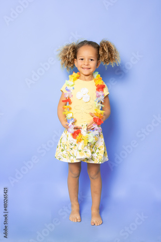 Full length photo of excited charming cute little girl with Happy little girl wearing Hawaiian necklace standing isolated over purple background. © Danko