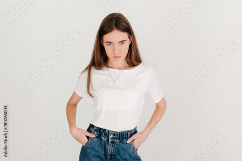 Portrait of angry young pretty woman in casual clothes, looking angrily at the camera on white background. Human emotions concept