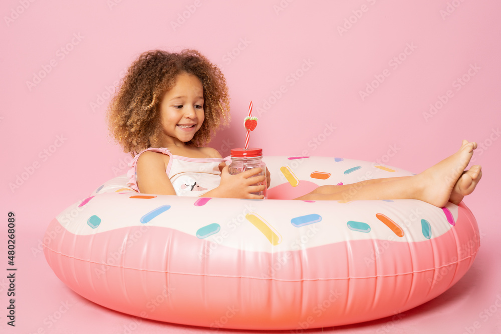 Portrait of happy little girl with inflatable rubber circle having fun isolated on pink background Portrait of happy little girl with inflatable rubber circle having fun isolated on pink background
