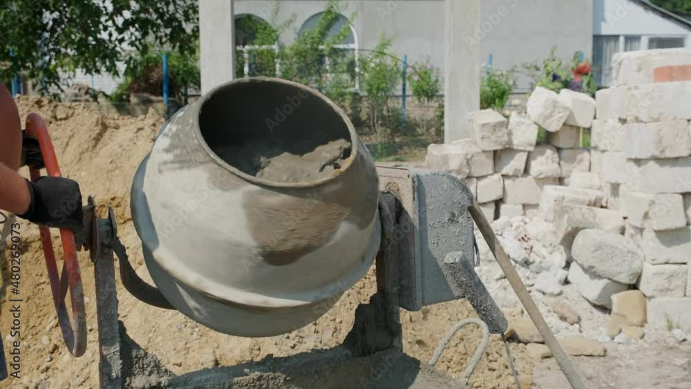 Old dirty concrete-mixer near sand heap at small construction site. Small portable cement mixing machine at home. Building site Old dirty concrete-mixer near sand heap at small construction site. Small portable cement mixing machine at home. Building site