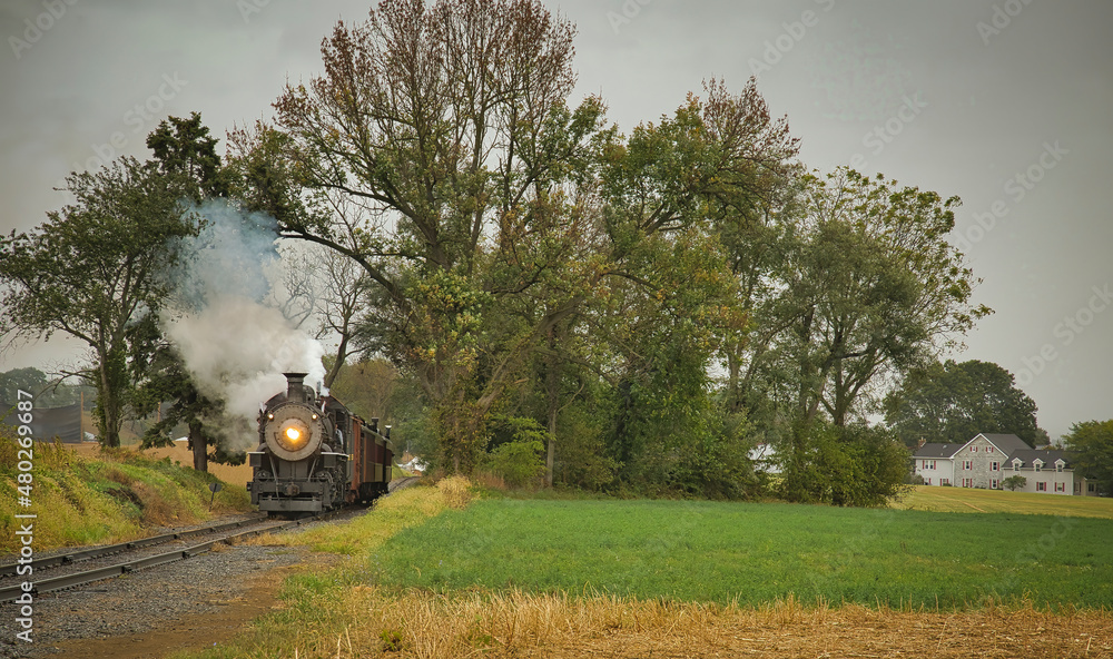 Obraz premium An Antique Restored Steam Freight Train Approaching Head on Blowing Smoke and Steam