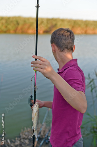 A young guy on a fishing trip caught a crucian fish.