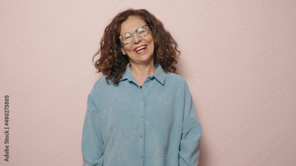 Middle age woman smiling confident pointing with finger over pink background Middle age woman smiling confident pointing with finger over pink background