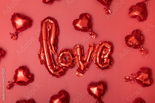 Festive background for Valentine's Day from Foil balloons shape heart and love word on red background