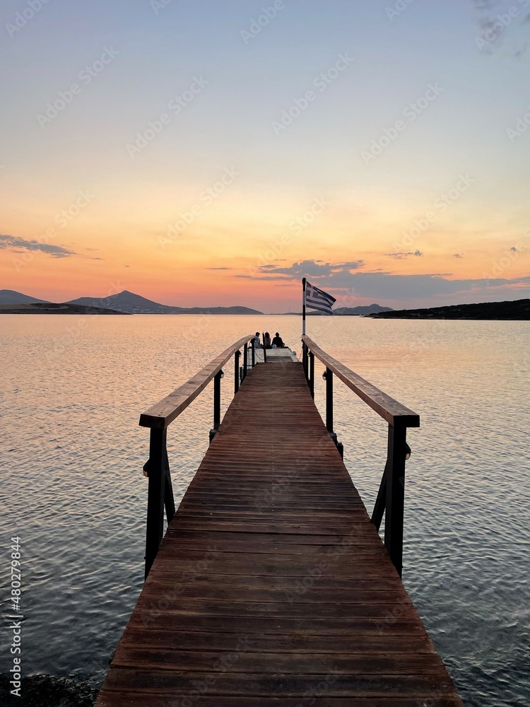 Jetty with a Greek flag at the time of sunset