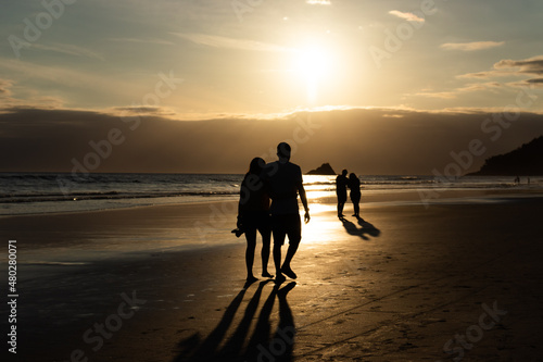 casal admirando o pôr-do-sol na praia no verão nas férias