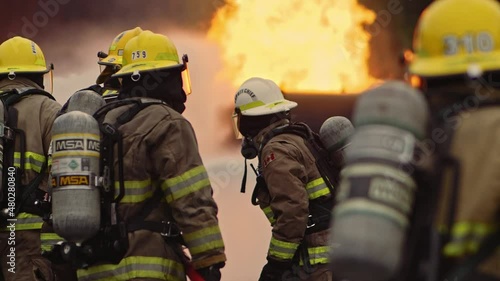Dramatic shot of firefighters in formation putting out roaring fire in slow motion photo