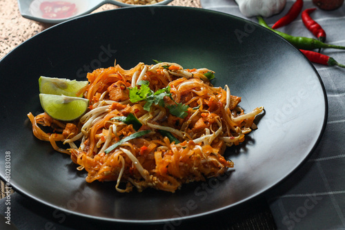 Thai Food Pad Thai (Thai national dish) Pad Thai on black plate with lime and seasonings.