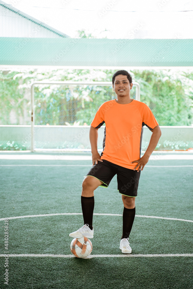 Futsal player in orange uniform poses both hands on waist