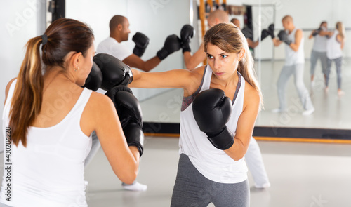 Fototapeta Naklejka Na Ścianę i Meble -  Young woman mastering self defense techniques, practicing punches at boxing gym