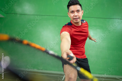 Close up of a male badminton player swinging a racket